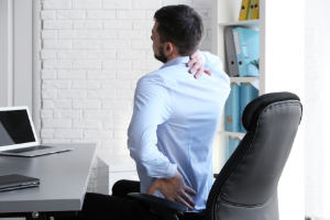 Man suffering back pain while sitting at work. How you can prove that your back pain was caused by a car accident.
