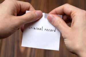 Hands of a man tearing a piece of paper with inscription criminal record
