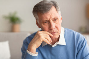 Grieving senior man sitting on couch after loss of family member