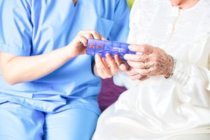 Caregiver giving medication to an elderly nursing home resident