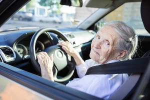 Adult child sitting with an elderly parent near a parked car