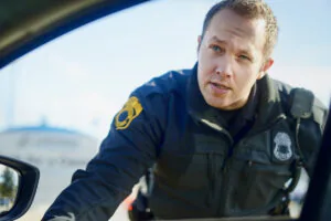 Traffic stop, police officer and talking at car for inspection, license check and law enforcement responsibility in city. Man, cop and question at vehicle window in roadblock, safety or investigationTraffic stop, police officer and talking at car for inspection, license check and law enforcement responsibility in city. Man, cop and question at vehicle window in roadblock, safety or investigation